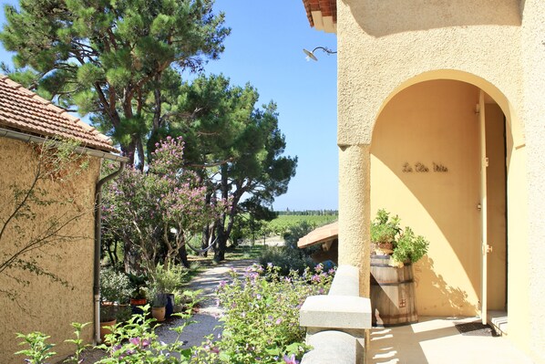 A courtyard with a pergola, potted plants, and a stone bench. - Le Clos Vitis - Chambres d'hôtes et gite (Violes)