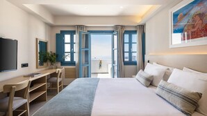 Ein Hotelzimmer mit einem großen Bett, einem Schreibtisch, einem Sessel, einem Fernseher und Meerblick.