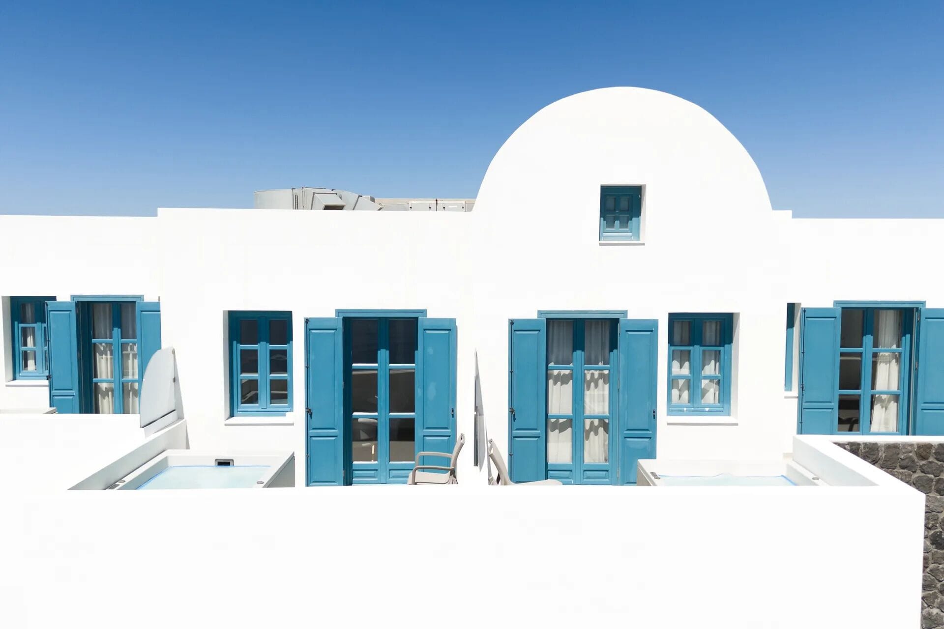 A white building with blue shutters and a dome-shaped roof.