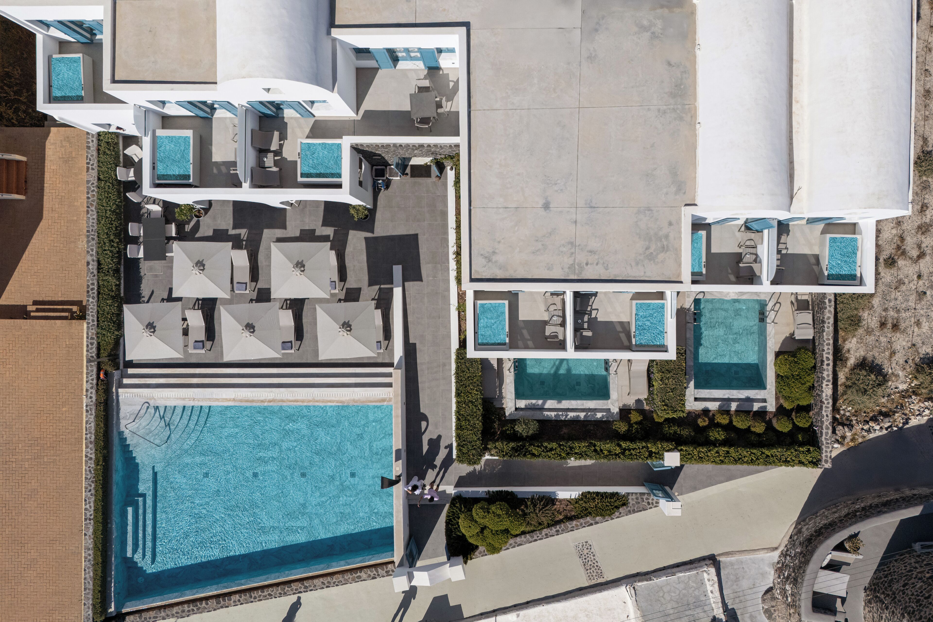 Ein Luftbild eines Resorts mit mehreren Schwimmbecken, Sitzgelegenheiten im Freien und einem großen zentralen Pool.