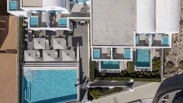 Ein Luftbild eines Resorts mit mehreren Schwimmbecken, Sitzgelegenheiten im Freien und einem großen zentralen Pool.