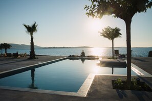 Una piscina con vistas al mar y montañas al fondo.