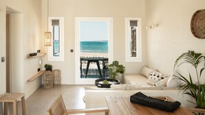 A beach view from a room with a wooden table, a sofa, and a wicker basket. - Seesoo Paros Beachfront Luxury Hideaway (Paros)