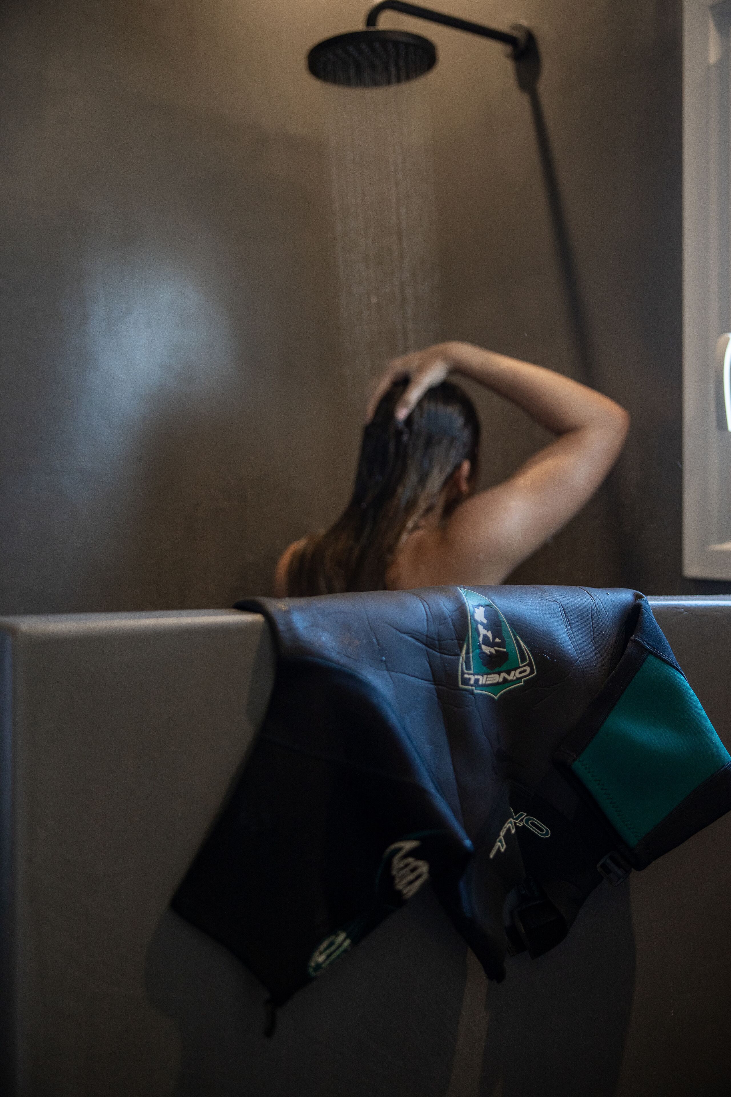 A shower area with a visible towel rack and a person in the background.