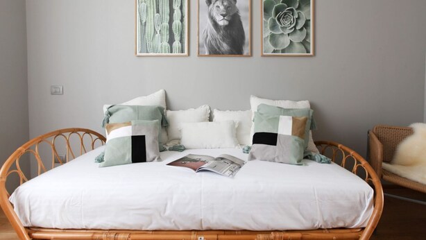 A bed with a white mattress, multiple pillows, and a magazine on it. There are three framed pictures on the wall above the bed. - Cà Bèla Vitruvio - Flat 2 (Milano)