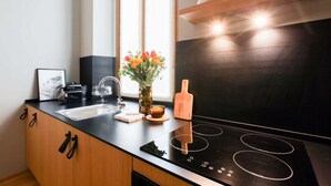 A modern kitchen with a black countertop, a built-in oven, and a wooden cabinet. - Cà Bèla Vitruvio - Flat 2 (Milano)