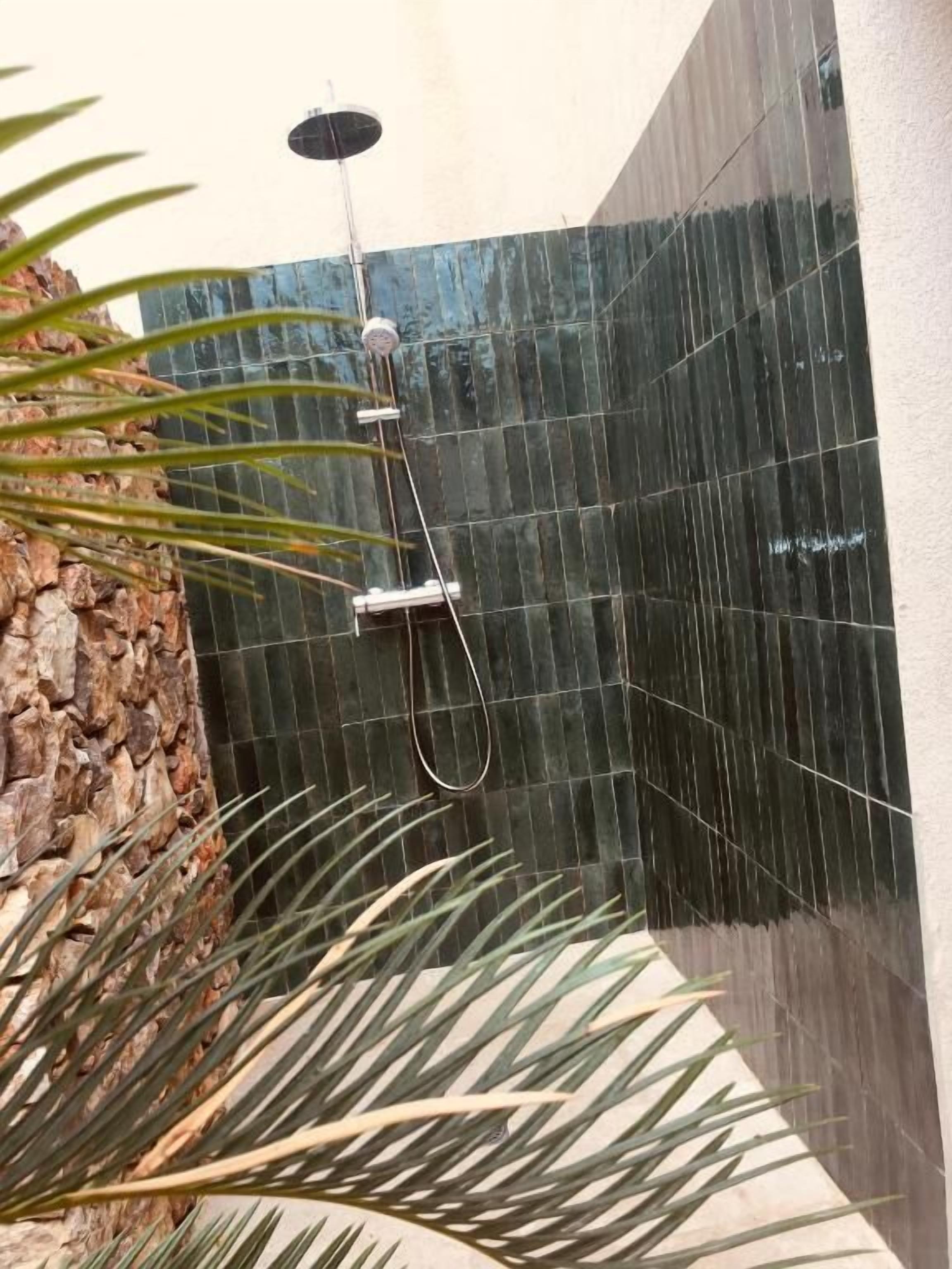 Un espace douche agrémenté d’un élément décoratif vertical à base d’eau et d’un mur en pierre.
