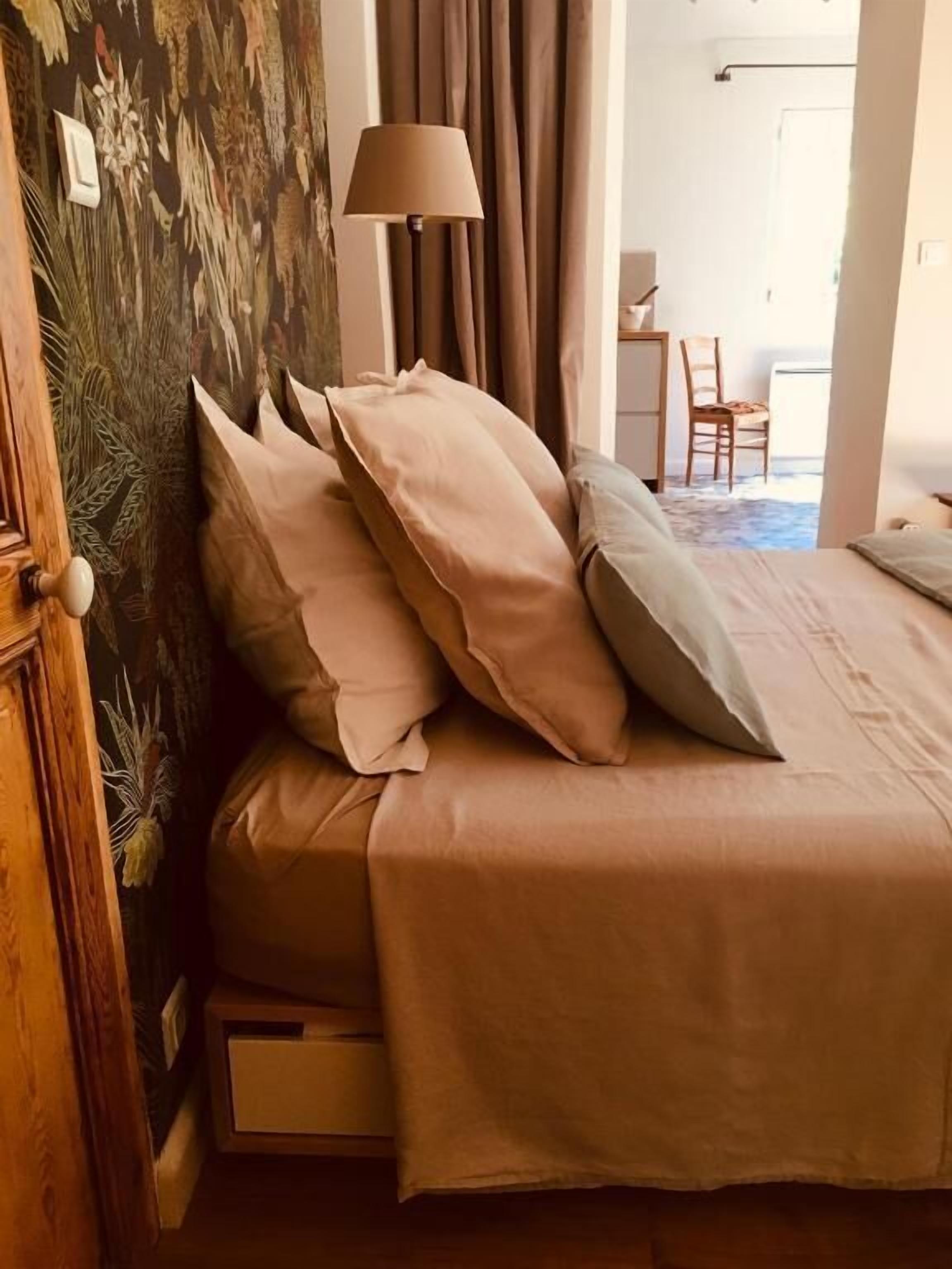 A bedroom with a bed, pillows, a lamp, and a view of a dining area.
