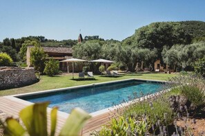 A rectangular swimming pool with a wooden deck, surrounded by greenery and a stone wall. - Bastide Sainte Trinide (Sanary-sur-Mer)