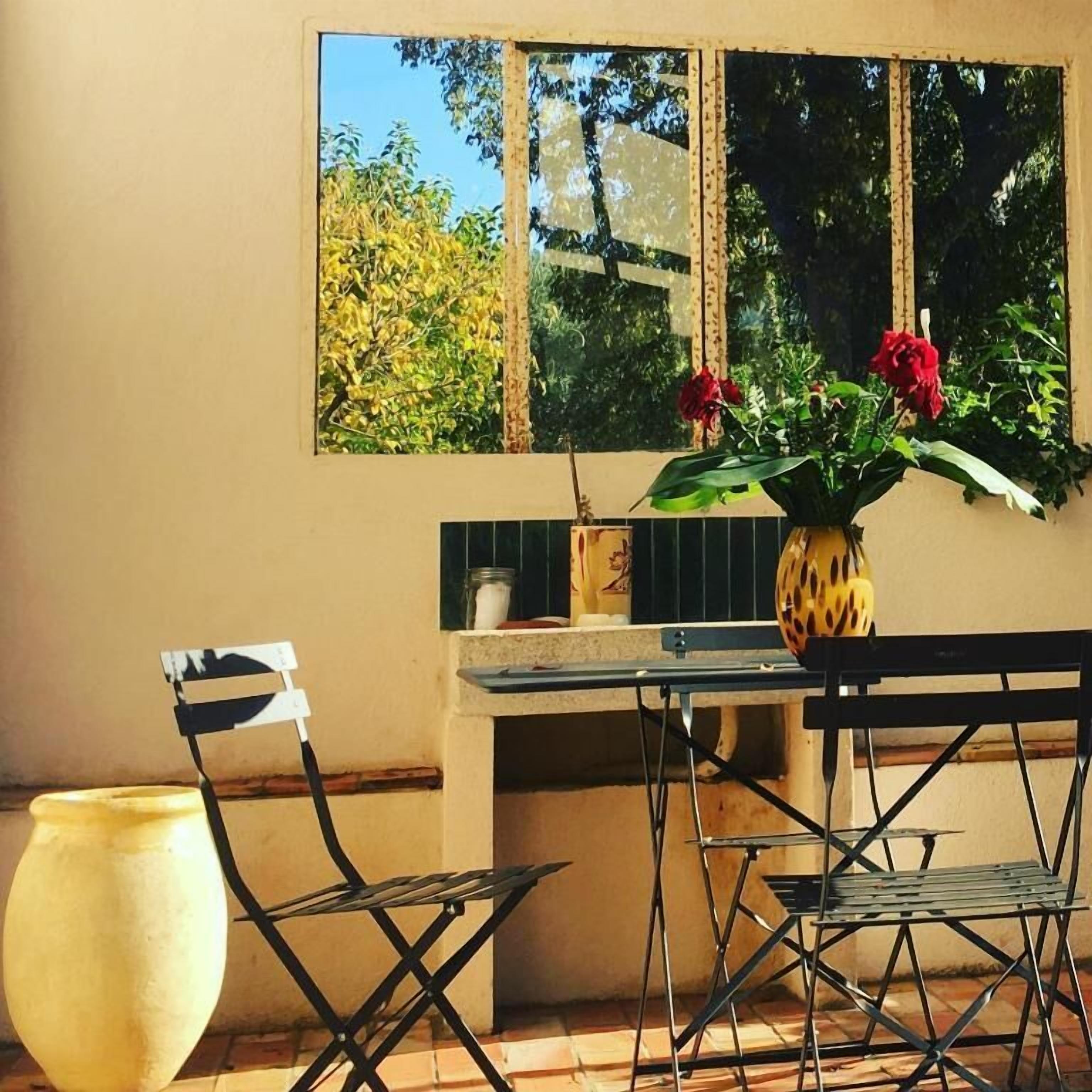 A dining area with a table, chairs, and a vase with flowers.