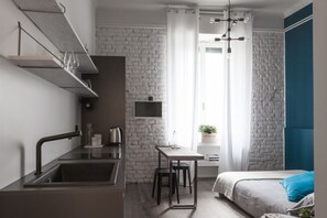 A modern room with a kitchen area, a dining table, and a bed.