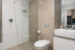 A modern bathroom with a glass shower enclosure, a toilet, and a sink with a mirror above it. - The Sentinel (Cape Town)