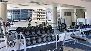 Un gimnasio con equipo de levantamiento de pesas, cintas de correr y mancuernas.