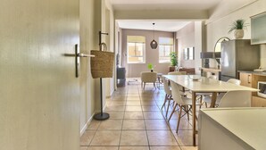 A modern kitchen with a dining area, featuring a large island, a refrigerator, and a TV. - The Piazza (Cape Town)