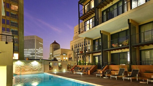 A rooftop pool area with lounge chairs and a view of surrounding buildings. - The Piazza (Cape Town)