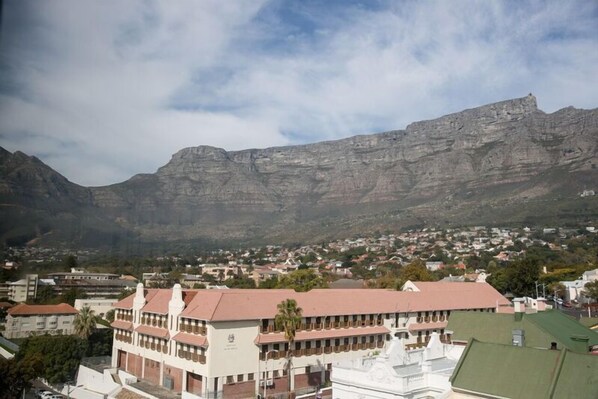 A building with a red roof and white walls, surrounded by a town and mountains. - On Kloof (Cape Town)