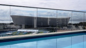 A swimming pool with a view of a modern building with a curved roof. - The Legacy II (Cape Town)