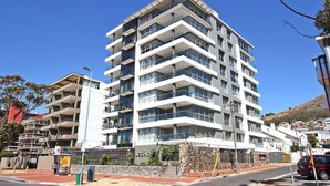 A multi-story hotel with balconies, a stone facade, and a clear blue sky. - The Legacy II (Cape Town)