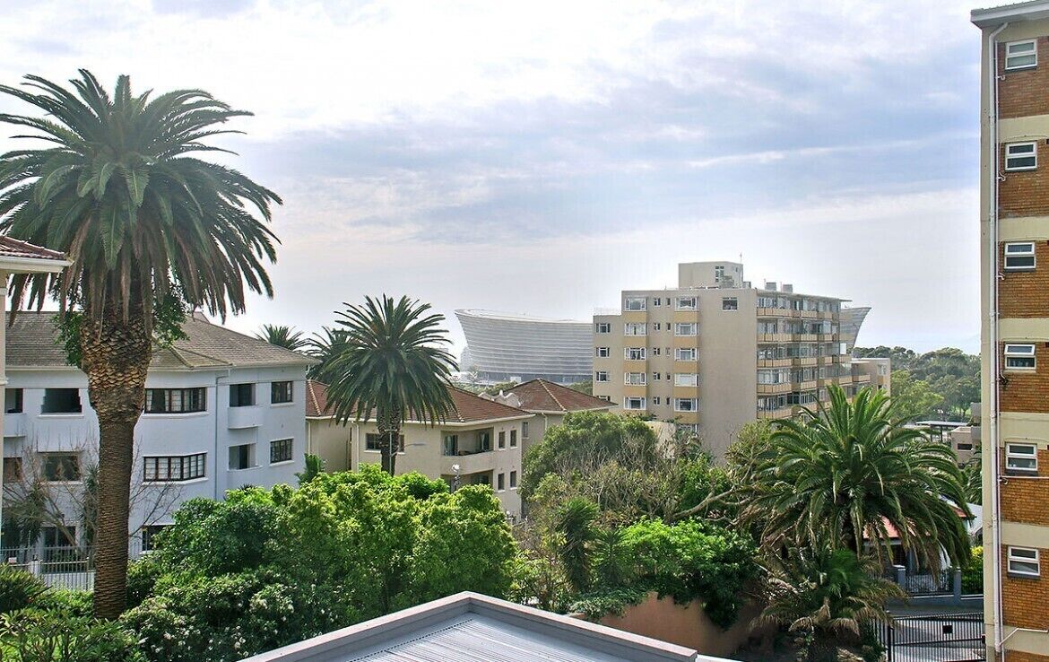 Zona residencial con edificios de varios pisos, palmeras y un edificio moderno curvo al fondo.