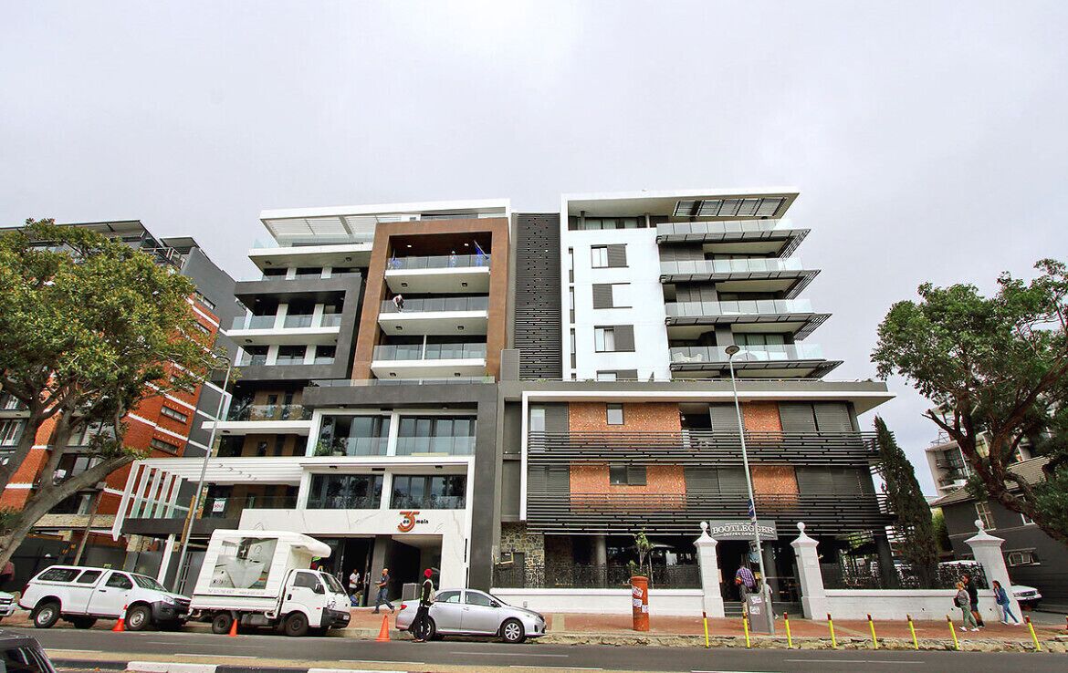 A multi-story building with a modern architectural design, featuring balconies on each floor and a mix of glass and brick facades.