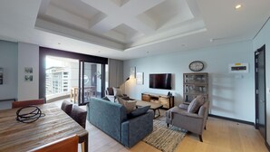 Una sala de estar moderna con un sofá, sillones, una mesa de comedor y un televisor.