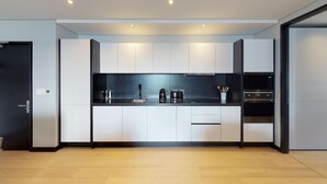 Una cocina moderna con armarios blancos, encimera negra y electrodomésticos de acero inoxidable.