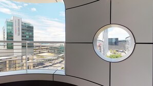 Un edificio moderno con un ventanal circular que ofrece vistas del paisaje urbano, incluyendo un edificio destacado con la señalización 'WEBBER WENTZEL'.
