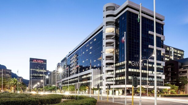 Un edificio moderno de varios pisos, con grandes ventanales y un llamativo letrero 'ABSA'.
