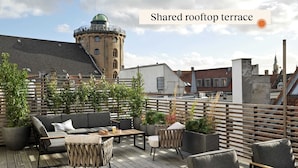 Una terrazza sul tetto in comune con posti a sedere all'aperto, piante in vaso e vista sulla città.