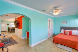 A room with a bed, a dining area, and a hallway.