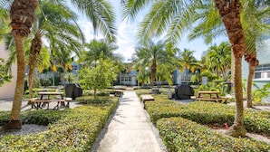 A pathway flanked by palm trees and benches, leading to a building with multiple windows.