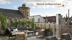 Una terrazza sul tetto in comune con posti a sedere all'aperto, piante in vaso e vista sulla città.