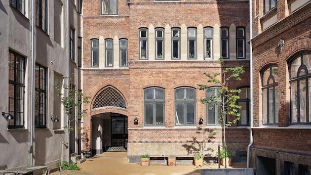 Un cortile con un edificio in mattoni, panchine e piante in vaso.