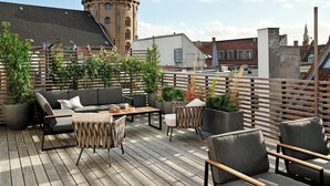 A shared rooftop terrace with outdoor seating and potted plants.