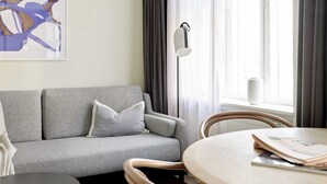 A modern living room with a grey sofa, a round wooden table, and a floor lamp.