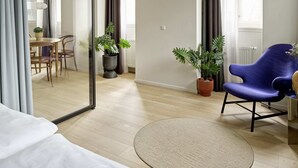 Una sala de estar moderna con un espejo grande, un sillón azul y dos macetas.