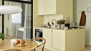 Cocina compacta con comedor, que incluye una isla central, horno integrado y cafetera.
