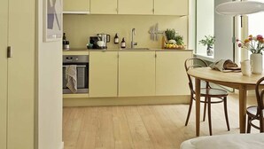 Cozinha compacta com área de refeições, piso de madeira e vista para o exterior.