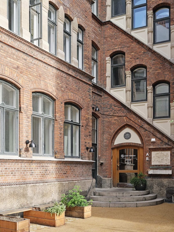 A multi-story brick building with large windows and a wooden door.