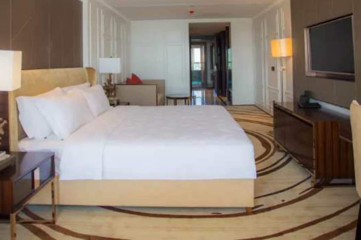 A hotel room with a large bed, a desk with a chair, a television, and a lamp.
