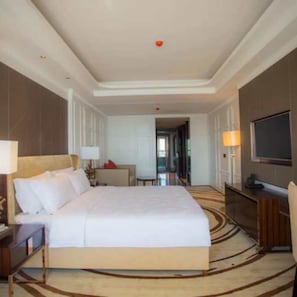 Habitación de hotel con una cama grande, un escritorio con una silla, un televisor y una lámpara.