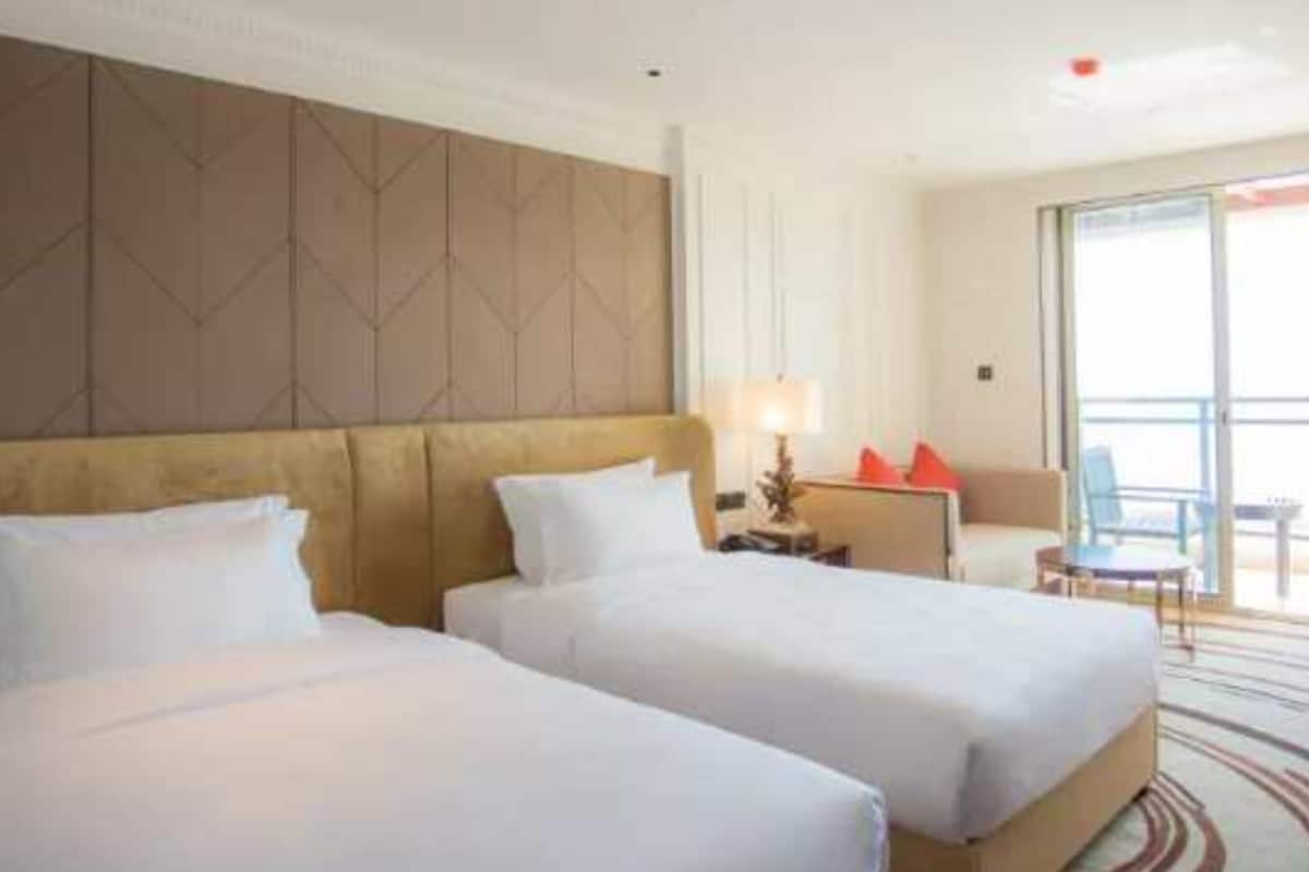 A hotel room with two beds, a large window, and a view of the outdoors.