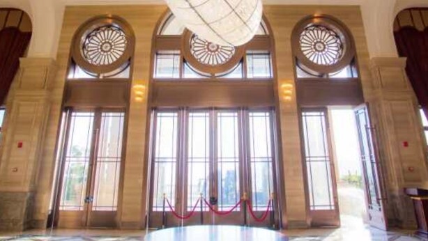 Un vestíbulo amplio con una gran mesa circular, ventanas de arco y un techo decorativo.