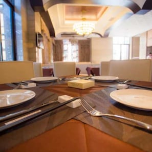 Un comedor con una mesa dispuesta para cuatro personas, incluyendo platos, cubiertos y una caja de pañuelos.
