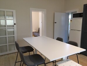 A modern kitchen with a white countertop, two chairs, a refrigerator, and a microwave.