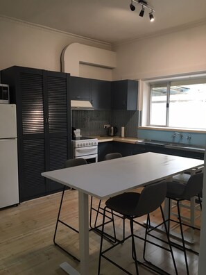 A compact kitchen with dark cabinetry, a white countertop, a stove, and a window providing natural light.