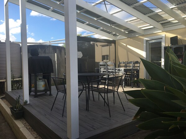 A covered patio with a table and chairs, a grill, and a water heater.