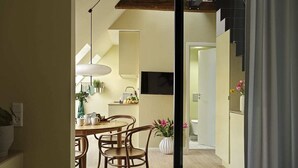 Ein modernes Hotelzimmer mit Bett, Essbereich mit Tisch und Stühlen, Küchenzeile und einer Treppe.