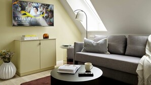 A modern living room with a sofa, a coffee table, a TV mounted on the wall, and a skylight. - Attic Studio Apartment for 2 (København)
