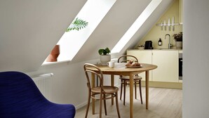 A modern loft with a dining area featuring a wooden table and chairs, a skylight, and a kitchen with a sink and cabinets. - Attic Studio Apartment for 2 (København)